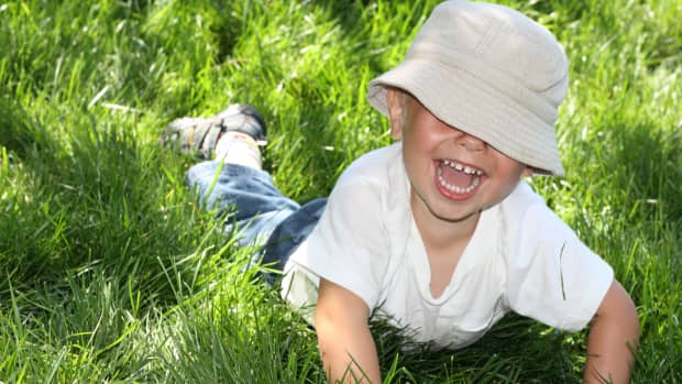 little boy with hat smiling in grass